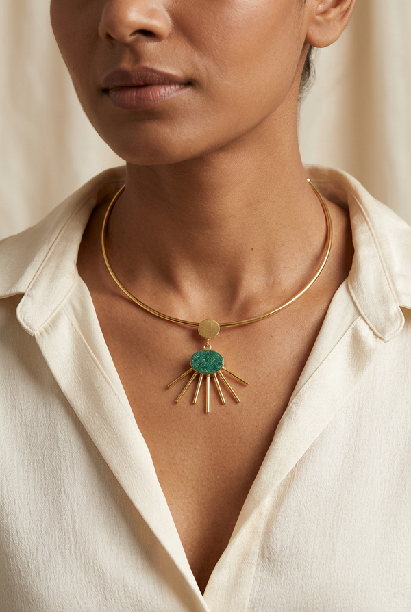 AI-generated styling image of Gold-Tone Green Stone Sunburst Pendant Necklace worn with an ivory blouse.